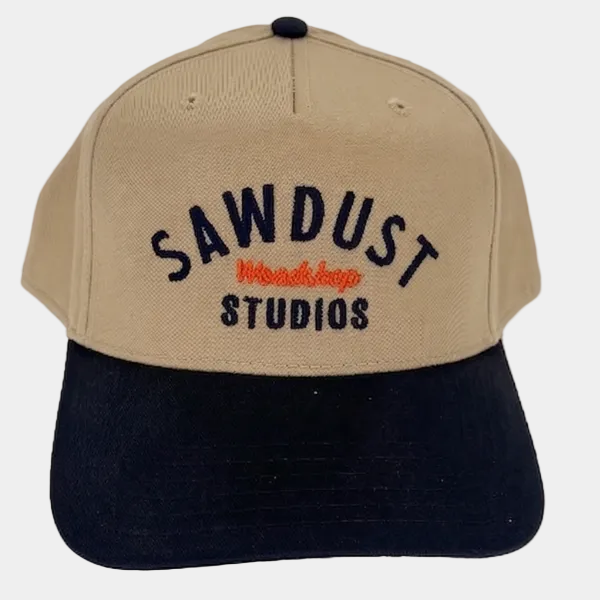 Beige and black cap with 'Sawdust Studios' text on a white background